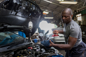 Obraz premium Car mechanic checking oil quality the engine motor car Transmission and Maintenance Gear. car mechanic in an auto repair shop is checking the engine.
