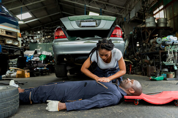 First aid support accident at work of worker at garage. Man worker has an accident on the floor in...