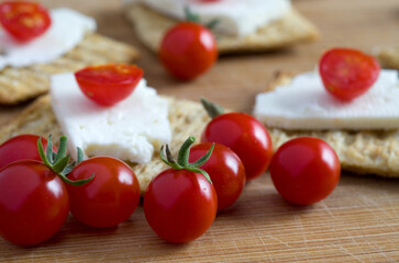 Macro Image of Baby Red Tomatoes with Feta Cheese and Crackers on Wood