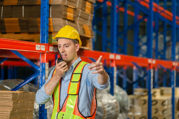 Warehouse worker working in factory warehouse industry and using radio talking communication, Foreman in hardhat safety vest with Two-Way radio working in logistics center