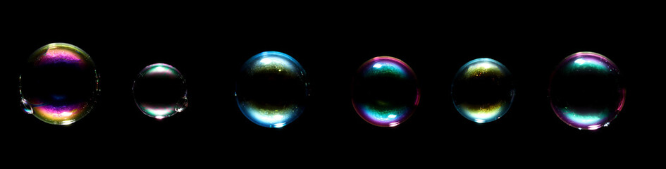 transparent globular shape soap bubbles flying on a black background.