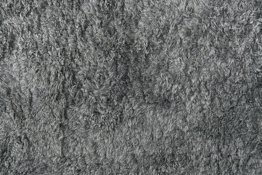 Grey soft fabric rug surface. Gray texture background of the furry carpet.