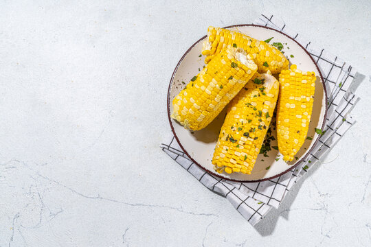 Boiled corn with butter and herbs. Ripe yellow organic cooked corn cobs, on a white kitchen table
