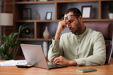 Tired african american businessman after exhausting paperwork taking off eyeglasses and feeling eye...