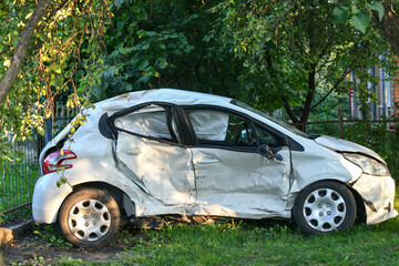 White microcar heavily damaged on the side, with airbags exploded. Car accident.