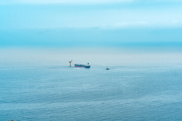 foggy seascape with a tanker near an oil terminal located far out to sea, top view