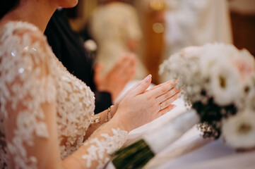 Ręce pary młodej złożone do modlitwy podczas ślubu - obrazy, fototapety, plakaty