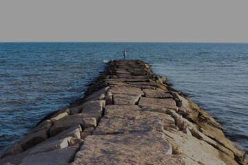 Person looking out on the water on a rock jetty