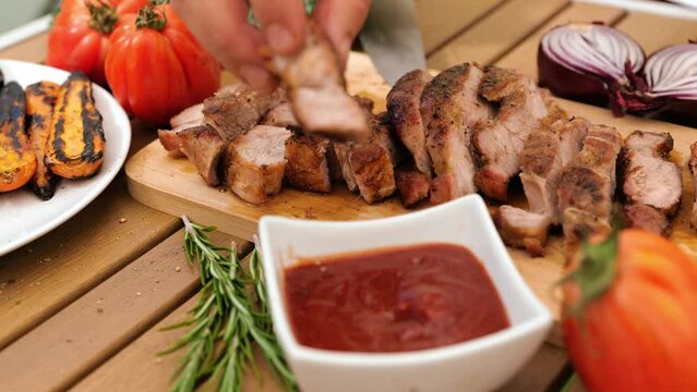 The man's hands, carefully choosing the grilled steak, soak it in the delicious tomato sauce.