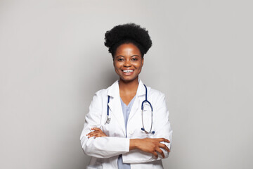 Portrait of young cheerful woman doctor with happy positive smile standing with arms crossed