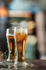 Glasses of light foamy beer with drops and splashes in bar lights background. Alcohol, entertainment, traditional drinks, Oktoberfest atmosphere concept. Copy space