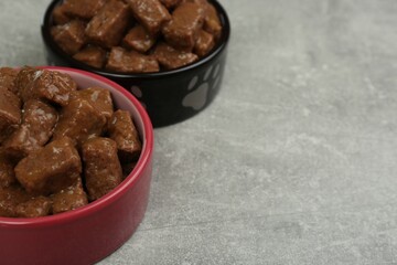 Wet pet food in feeding bowls on light grey background. Space for text