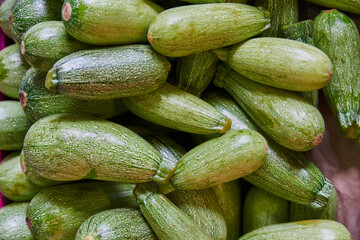 Stacked zucchini on a shelf for sale within a market