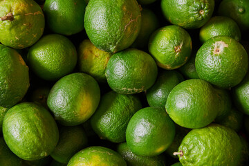 Green lemons placed on a shelf for sale at a market