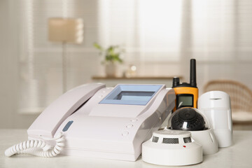 Intercom, CCTV camera, walkie talkie, smoke and movement detectors on white table indoors. Home security system