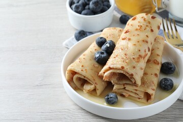 Delicious crepes with blueberries and honey on white wooden table. Space for text