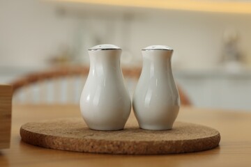 White ceramic salt and pepper shakers on wooden table indoors