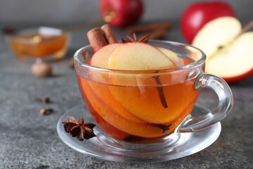 Aromatic hot mulled cider on grey table, closeup