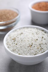 Different kinds of salt in bowls on grey table, closeup