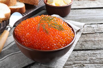 Bowl with delicious red caviar and dill on wooden table