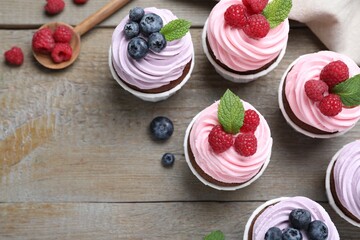 Sweet cupcakes with fresh berries on wooden table, flat lay. Space for text
