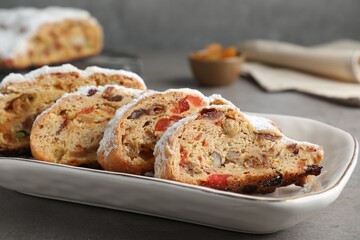 Traditional Christmas Stollen with icing sugar on grey table, closeup
