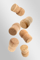 Many corks of sparkling wine bottles falling on light grey background