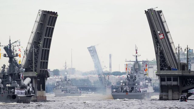 A lot of warships goes along the Neva River under open bridges at the time of the celebration of the day of Navy in cloudy weather, military motor boat