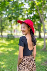 Portrait photo of the sexy back of a beautiful moment of a young asian beautiful lady with red hat happily posing and relax in a garden park strolling