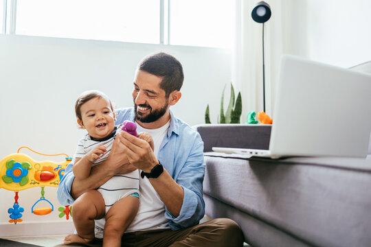 Father working with his baby boy in home office with laptop. Work from home concept