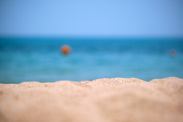 Close up of clean yellow sand surface covering seaside beach with blue sea water on background. Travel and vacations concept