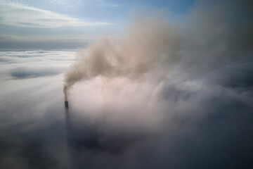 Coal power plant high pipes with black smoke moving upwards over clouds polluting atmosphere. Production of electrical energy with fossil fuel concept