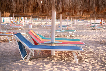 Empty deck chairs on sandy beach sea side in summer resort. Vacations and getaway concept