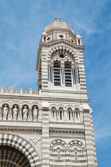 Fototapeta premium Right tower of the Marseille Cathedral in front of a blue summer sky. Sumer vacation sightseeing. Old, beautiful, romanesque-style cathedral in Marseille, France. Sightseeing in southern France. 