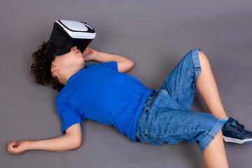 child playing with virtual reality goggles. lying on the floor