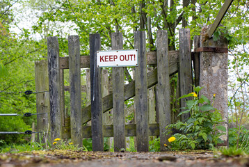 The wooden country gate and fence with sign Keep Out.