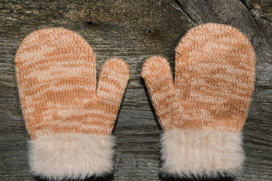 Beige Woolen Mittens On A Wooden Background. View From Above.