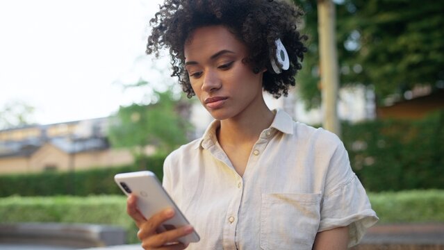 Beautiful woman listening to music in headphones, using app on smartphone
