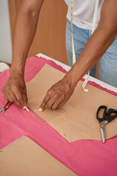 Male tailor doing patterns with chalk on pink fabric