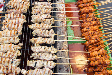 A meat on a stick is grilled on the grill. Preparing chicken on a stick in a Thai market
