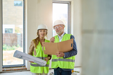 Realtor with drawings, and foreman with folders in their hands