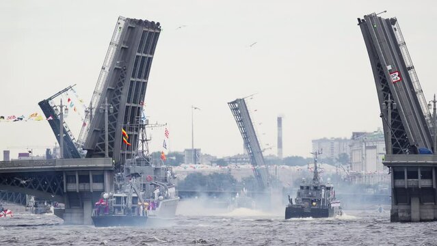 A lot of warships goes along the Neva River under open bridges at the time of the celebration of the day of Navy in cloudy weather, military motor boat