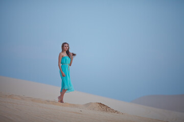 Fototapeta na wymiar Beautiful young woman meeting dawn in the desert. The start of a new day. Freshness of the morning. Long light hair.