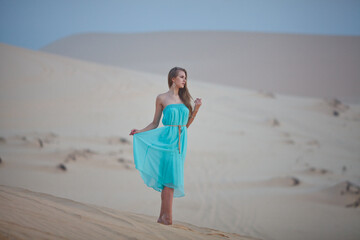 Beautiful young woman meeting dawn in the desert. The start of a new day. Freshness of the morning. Long light hair.