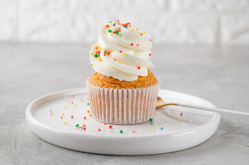 Delicious vanilla cupcakes with cream cheese and sugar candy on a gray background. Dessert for birthday. selective focus, copy space.