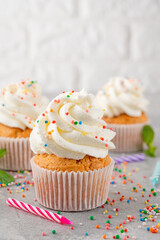 Delicious vanilla cupcakes with cream cheese and sugar candy on a gray background. Dessert for birthday. selective focus, copy space.
