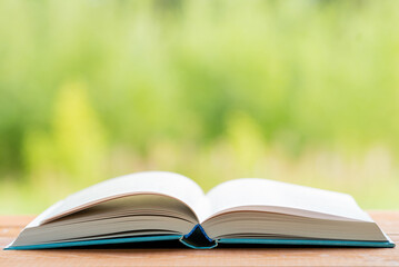 Open book on wooden table on natural background. Concept of reading books. Image with shallow depth of field.