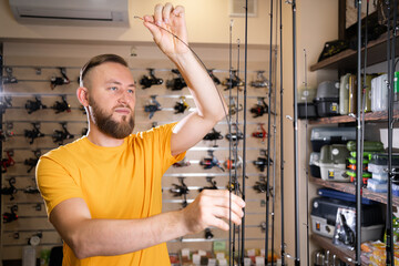 Man chooses ocean fishing rod in the sports shop