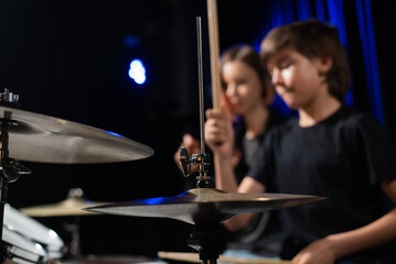 Young woman teaching boy to play drums.
