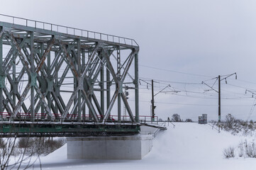 Old railway bridge across the river in winter
